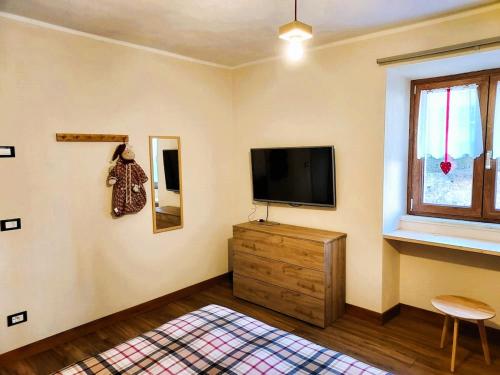 a living room with a television and a wooden dresser at Pasubio 13 in Selvino