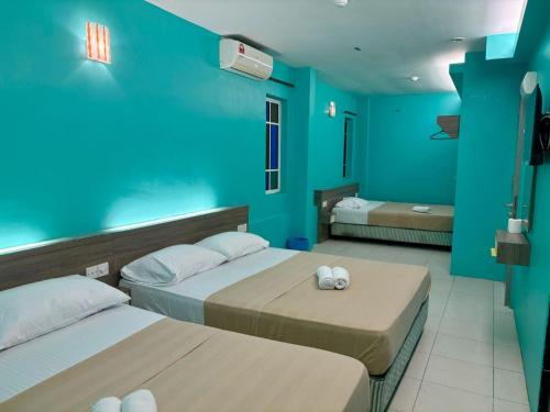 a bedroom with two beds and a blue wall at Qish Hotel Melaka in Malacca