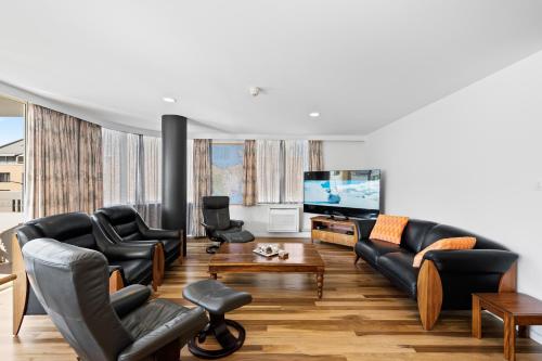 a living room with black leather furniture and a flat screen tv at Jenatt Apartments Salamanca in Hobart