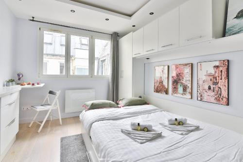 - une chambre blanche avec un grand lit et une cuisine dans l'établissement Chic Studio near Arc de Triomphe, à Paris