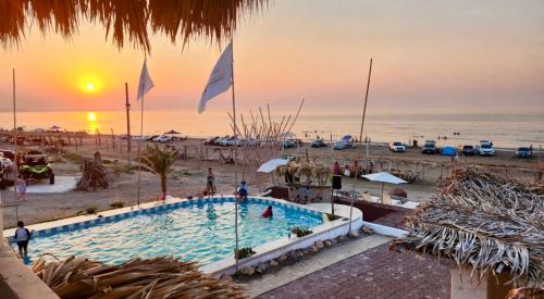 a swimming pool next to a beach with the sunset at Casa de Playa en Antón Lizardo con alberca privada y club Playa in Heroica Alvarado
