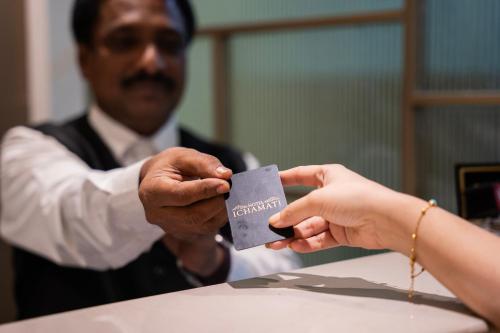 a man is handing a woman a car card at Hotel Ichamati in Kolkata