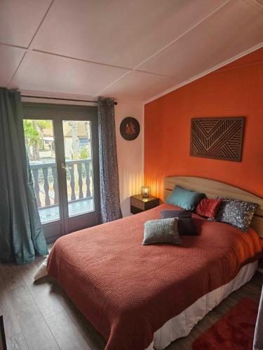 une chambre avec un grand lit avec un mur orange dans l'établissement Maison tout confort 4 ch 8p domaine privé avec piscines, et plage à 10 min à pied, à Portiragnes