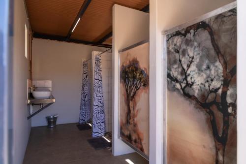a row of stalls in a bathroom with paintings on the walls at Spreetshoogte Campsite in Namibgrens