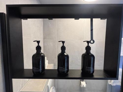 three black bottles sitting on a shelf in a bathroom at Near Amsterdam and airport, 90m2, privacy! in Hoofddorp