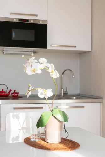 a vase with white flowers on a table in a kitchen at Cadenabbia Lake side Apartments in Griante Cadenabbia