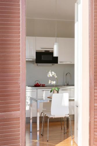 a kitchen with a table and white chairs at Cadenabbia Lake side Apartments in Griante Cadenabbia
