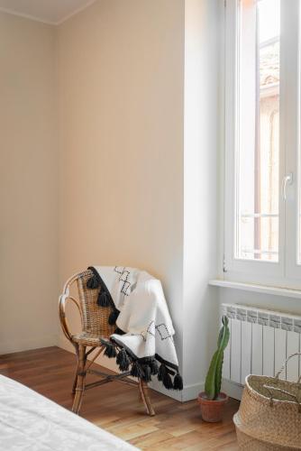 a wicker chair with a blanket on it in a bedroom at Cadenabbia Lake side Apartments in Griante Cadenabbia