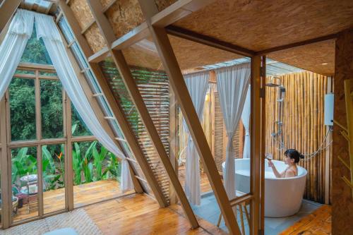a woman in a bath tub in a room with windows at บ้านธารหมอก แอท สะปัน in Ban Huai Ti