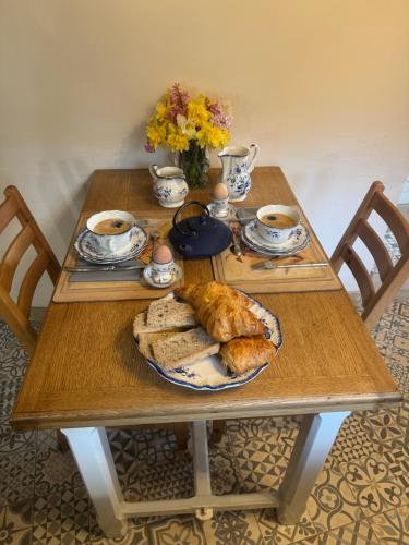 una mesa con un plato de pan y tazas de café en La Papèterie chambres de charme, en Gavaudun