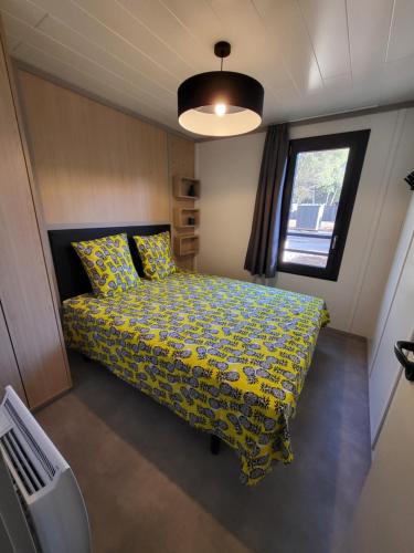 - une chambre avec un lit doté d'une couette jaune et d'une fenêtre dans l'établissement Cottage Cap d Agde, à Agde