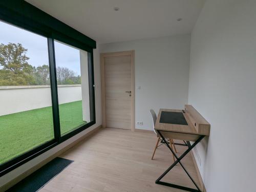 une pièce avec un bureau et une grande fenêtre dans l'établissement Maison familial dans le golf, au Tronchet
