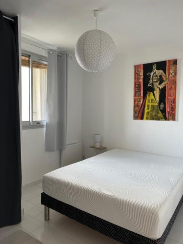 une chambre blanche avec un lit et un tableau au mur dans l'établissement Appartement 2 pièces + cabine, 6 couchages, au Grau-du-Roi