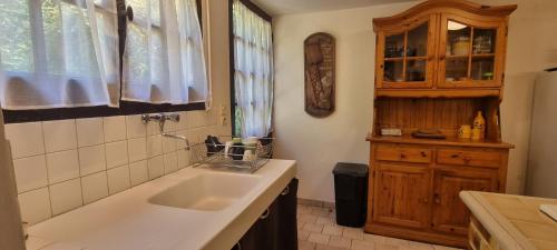 a kitchen with a sink and a wooden cabinet at Gite de l'étang in La Puisaye