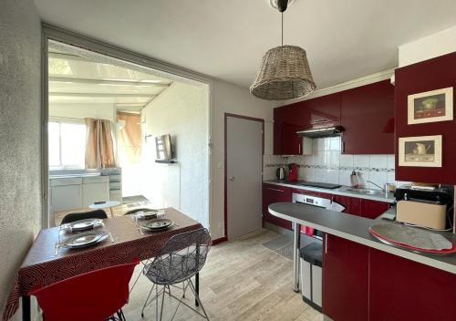 une cuisine avec des armoires rouges et un grand îlot avec des chaises dans l'établissement Windy Barcarès 200 m de la mer, au Barcarès