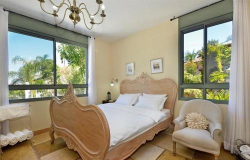 a bedroom with a large bed and a chair and windows at אחוזת יוסף-וילה מהממת למשפחות עם 2 בריכות וג'קוזי in Hatzor haglilit