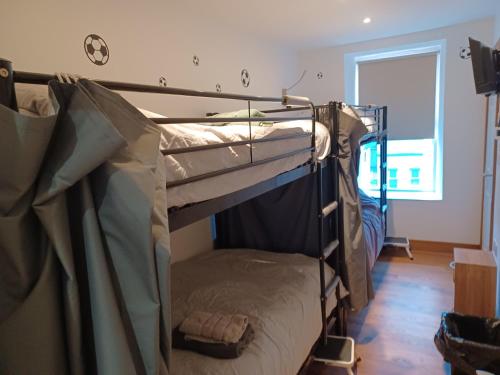 two bunk beds in a room with a window at Voyage Hostel - Beds & Rooms with shared kitchen in Douglas