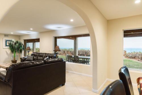 a living room with a black leather couch and large windows at Golden Sands Pearl - Florida's Top - ALL Private Beachfront with NEW Pickleball Court, Pool, Spa in Indialantic