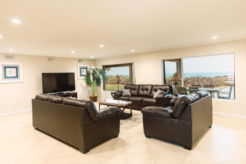 a living room with leather furniture and a flat screen tv at Golden Sands Pearl - Florida's Top - ALL Private Beachfront with NEW Pickleball Court, Pool, Spa in Indialantic