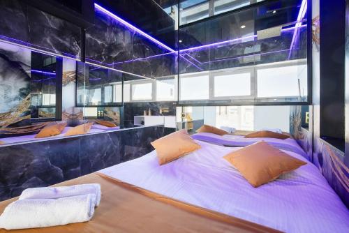 - une chambre dotée d'un grand lit avec des draps et des oreillers violets dans l'établissement Village Naturiste R4N SeaGold Port Nature II, au Cap d'Agde