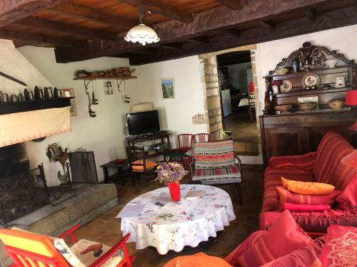 un salon avec un canapé rouge et une table dans l'établissement Maison de campagne Les loirs, à Lespinassière