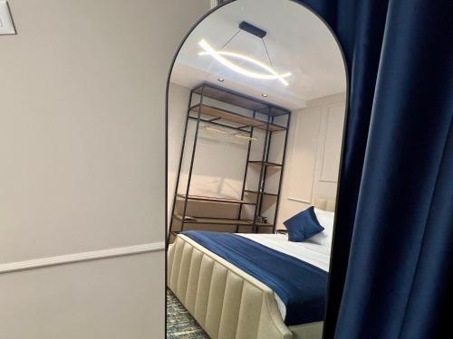 a mirror in a room with a bed and a blue curtain at The Harmony Duo in Tirana