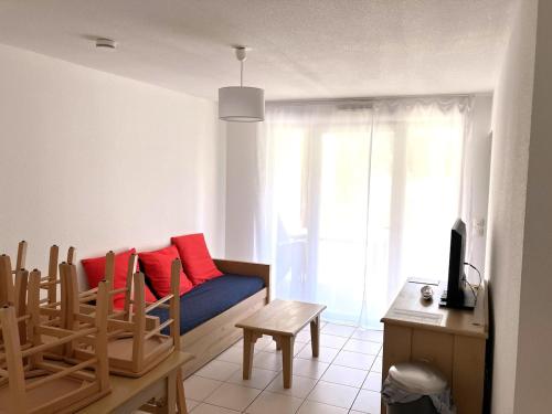 - un salon avec un canapé bleu et des oreillers rouges dans l'établissement Appartement plage piscine tennis, à Ondres