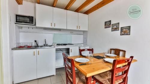 une cuisine avec des armoires blanches et une table en bois dans l'établissement Studio mezzanine Seringas, à Plage-des-Demoiselles