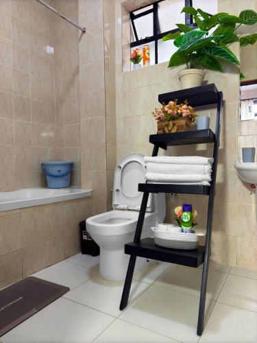 a bathroom with a toilet and a shelf with towels at The Home Kololo in Kampala