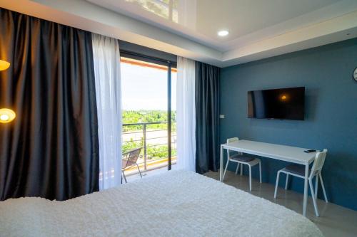 a bedroom with a bed and a desk and a window at The Urban Tropical Apartments in Mai Khao Beach