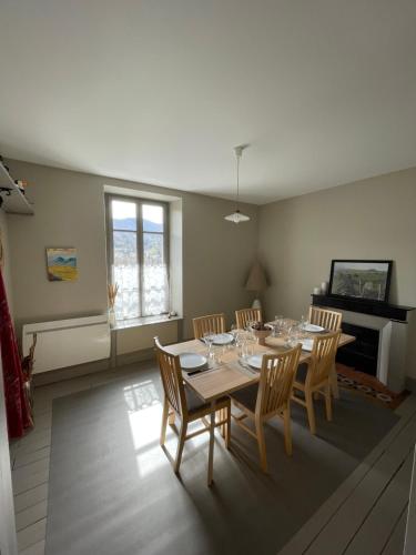 ein Esszimmer mit Tisch und Stühlen und einem Kamin in der Unterkunft Appartement Le feron in Vic-sur-Cère