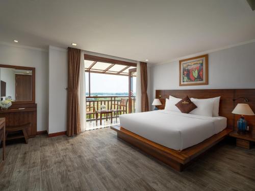 a bedroom with a large white bed and a balcony at Hoi An Odyssey Hotel & Spa in Hoi An