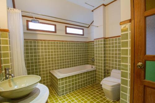 a green tiled bathroom with a sink and a toilet at Rich Lanna House in Chiang Mai