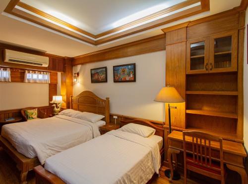 a hotel room with two beds and a lamp at Rich Lanna House in Chiang Mai
