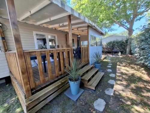 加斯泰Mobil-home Camping Siblu La Reserve ****的一座带木门廊的房屋,种植了两株盆栽植物