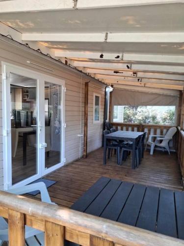 une véranda avec une table et une cuisine dans l'établissement Mobil-home Camping Siblu La Reserve ****, à Gastes