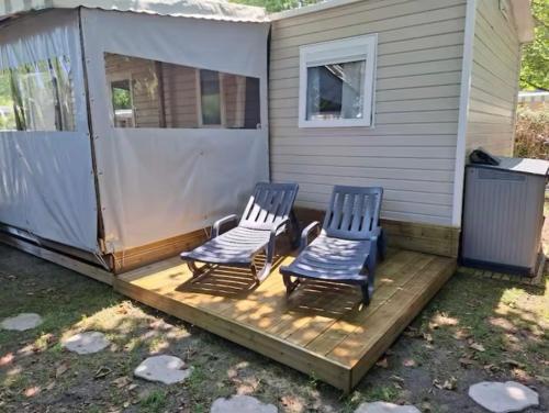 2 chaises assises sur une terrasse à côté d'une maison dans l'établissement Mobil-home Camping Siblu La Reserve ****, à Gastes