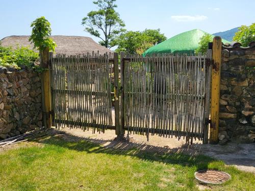 a wooden fence with a stone wall at Naganeupseong Jandi House in Suncheon