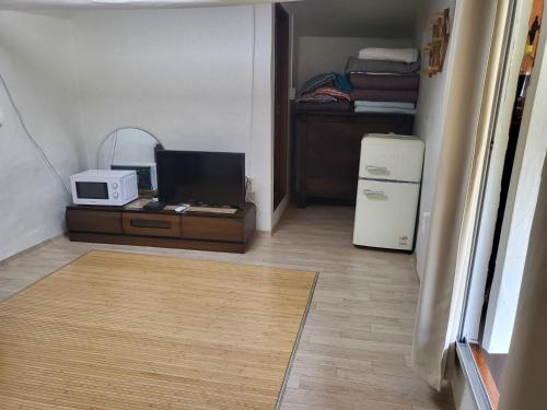 a room with a desk with a microwave and a refrigerator at Naganeupseong Jandi House in Suncheon
