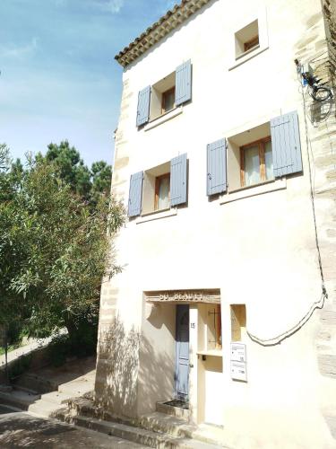 un vieux bâtiment blanc avec des fenêtres aux volets bleus dans l'établissement Maison de village avec superbe terrasse en pierre, à Caromb