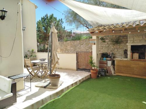 un patio avec un parasol et une table et un tableablish dans l'établissement Maison de village avec superbe terrasse en pierre, à Caromb