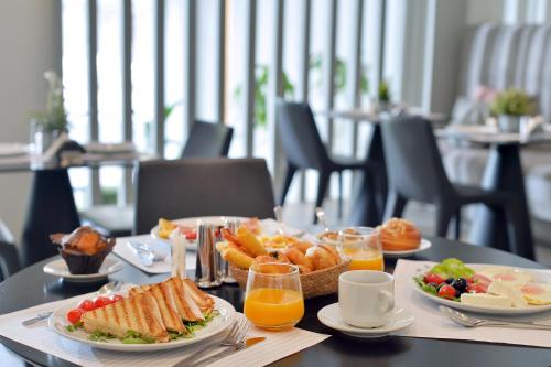 a table topped with plates of food and orange juice at Alva Athens Hotel in Athens