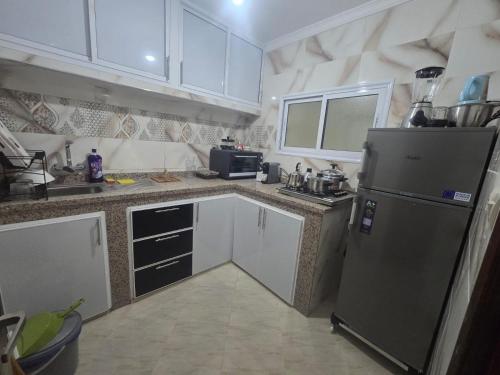a kitchen with a stainless steel refrigerator and white cabinets at Appartement Laayoune in Laayoune