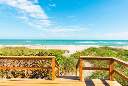 two benches sitting on a boardwalk near the beach at Golden Sands Pearl - Florida's Top - ALL Private Beachfront with NEW Pickleball Court, Pool, Spa in Indialantic