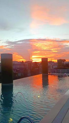 a swimming pool with a sunset in the background at Baguio Condo - City Hub - Urban Oasis in Pines with Pool & Mountain View in Baguio