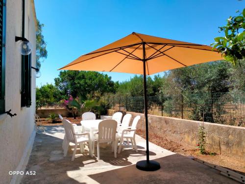 a table with white chairs and an orange umbrella at Casetta nel Verde in Locogrande