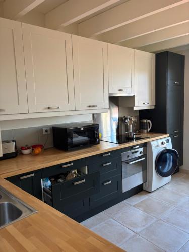 une cuisine avec des armoires blanches, un évier et un micro-ondes dans l'établissement Charme et confort au cœur de Versailles, à Versailles