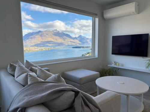 a living room with a couch and a large window at Takitimu Villa Remarkables View - Boutique Luxury, Private Bath with Stunning View in Queenstown