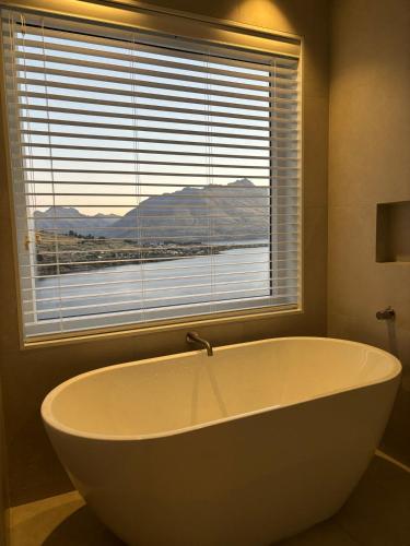 a large white bath tub in a bathroom with a window at Takitimu Villa Remarkables View - Boutique Luxury, Private Bath with Stunning View in Queenstown