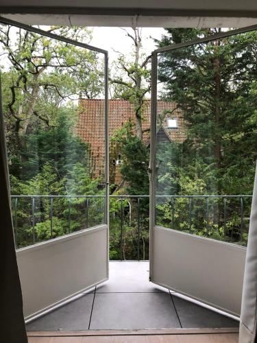 an open glass door to a balcony with trees at Bright Family Villa on Dune in Wassenaar in Wassenaar